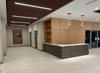 A reception area with a brown wooden reception desk and a large abstract painting on the wall.